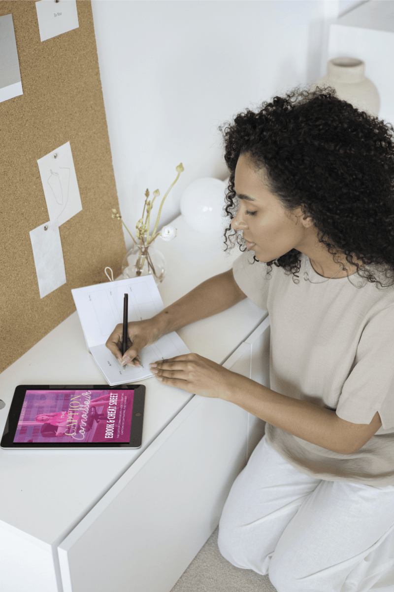 A woman sitting at a desk taking notes while reading the ebook